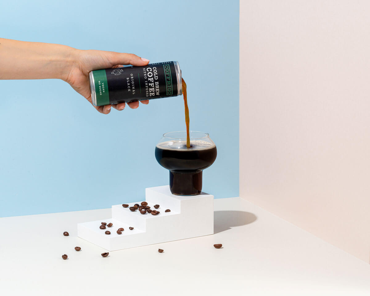 Dose Cold Brew Kaffee ORIGINAL BLACK in der Hand gehalten und in ein Glas eingeschenkt.