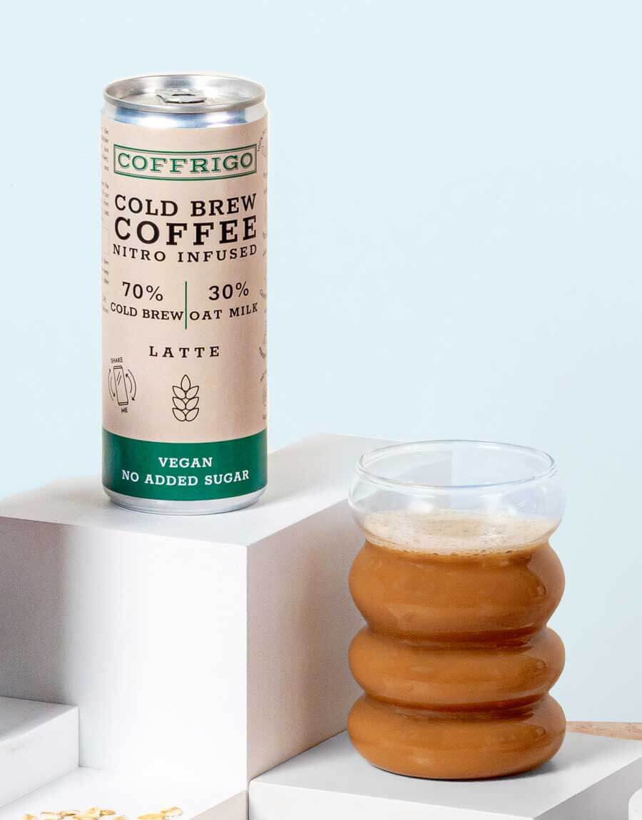 Dose von COFFRIGO's Cold Brew Kaffee OAT MILK LATTE neben eingeschenkten Glas